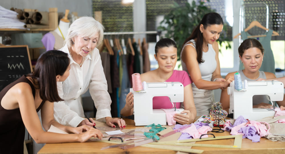 Elderly female teacher explains to group how to draw pattern