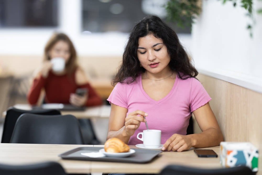 Attractive female sitting alone at table in cozy cafe, drinking fragrant coffee