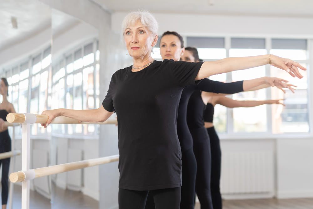 Senior woman maintaining second position at ballet barre
