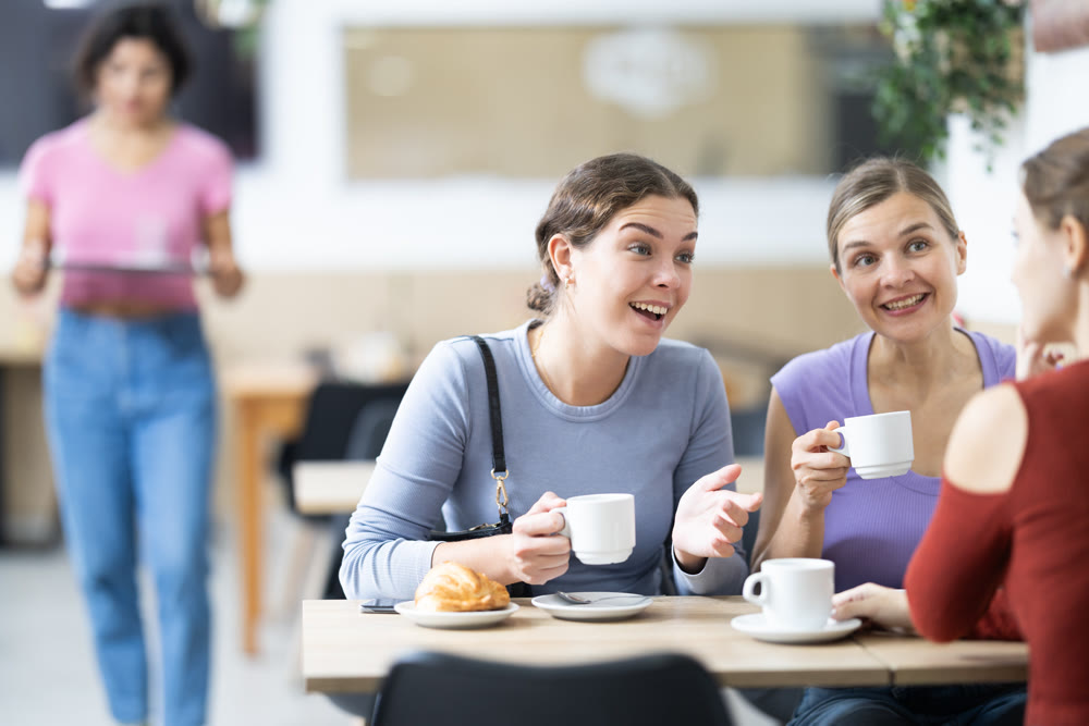 Three girlfriends drinking coffee and chatting