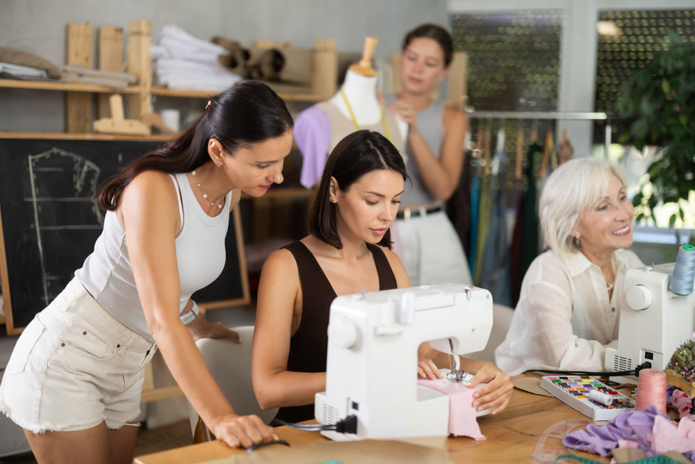 Young woman working at machine during group sewing course