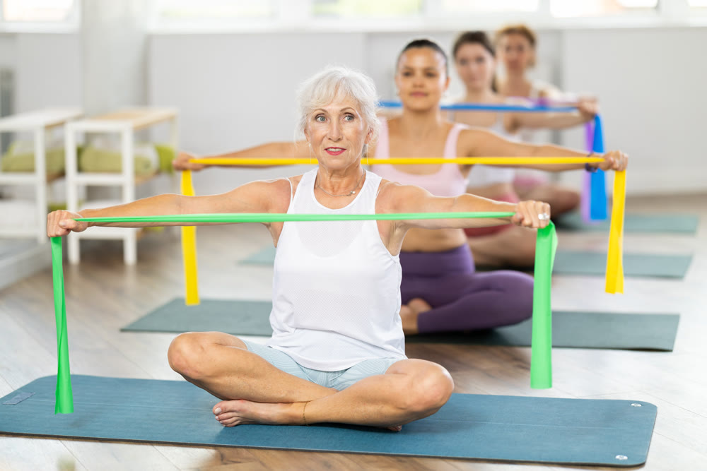 Elderly woman exercises with pilates band