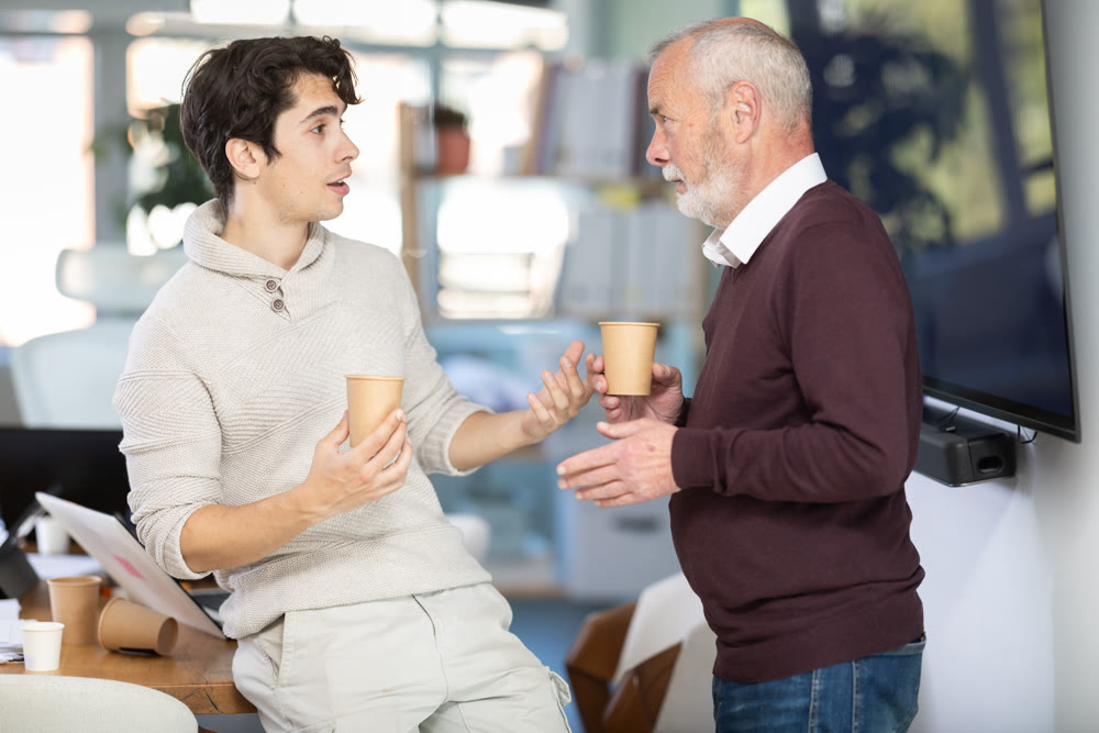 Two office workers drink coffee and chat during work break