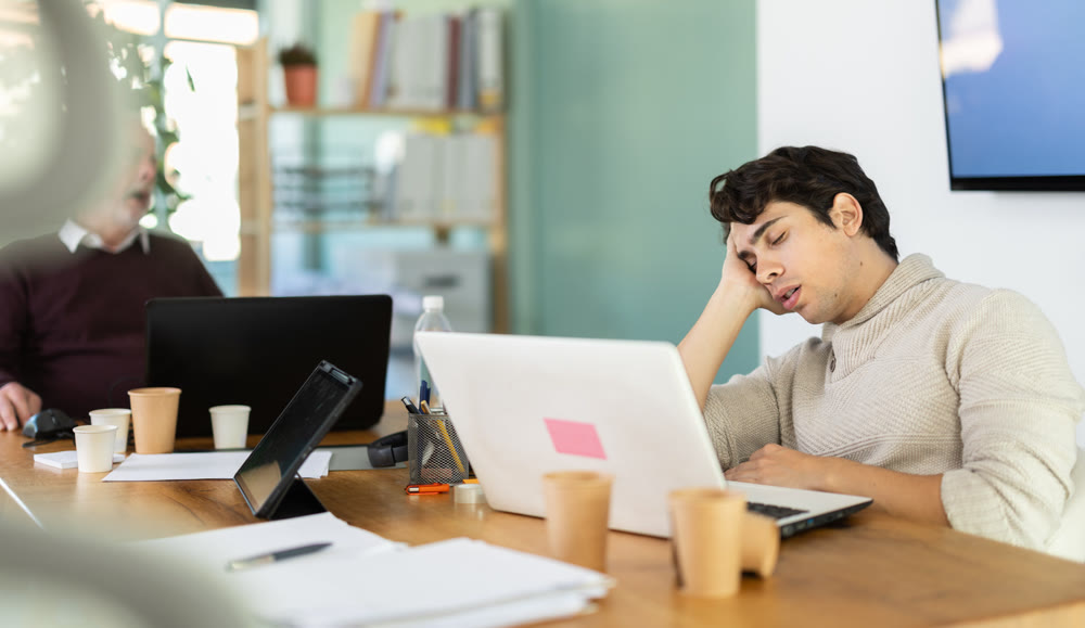 Wearied senior man and guy colleagues are dozing near workplace in office