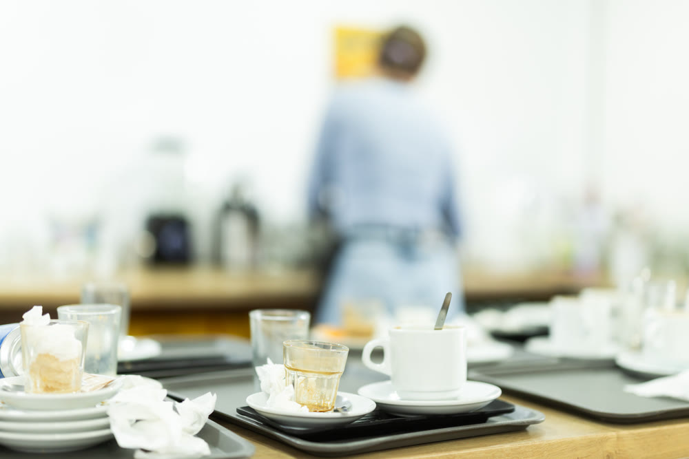 Messy counter in cafeteria cluttered with used dish