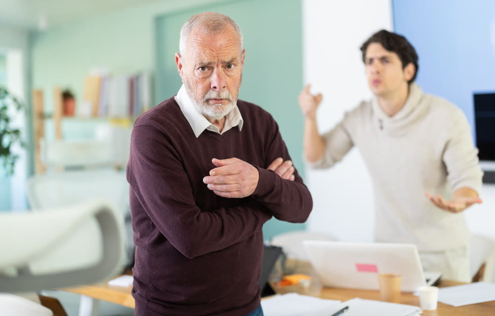 Disgruntled young boss yells and swears at older employee.