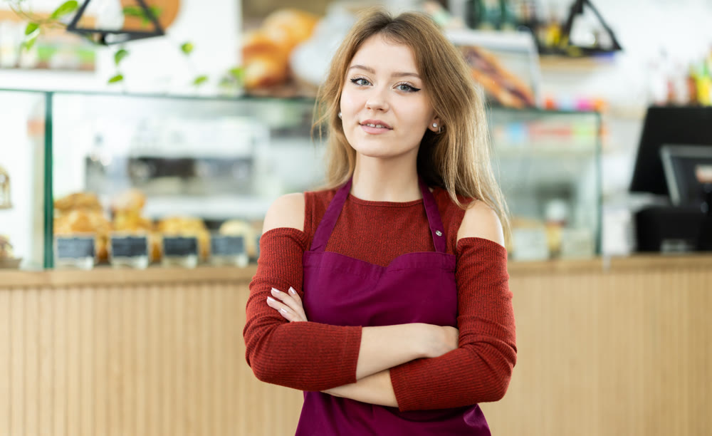 Female cafe employee greets guests of establishment