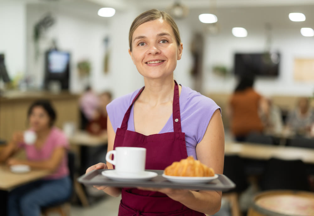 Young female waiter carries order for cafe customer