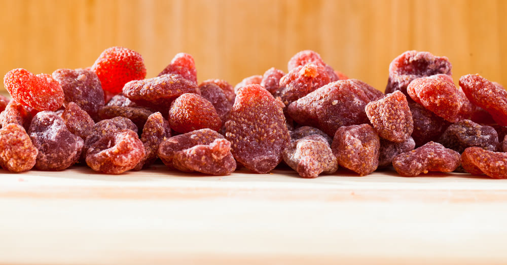 Tasty dried red strawberry berries on wooden surface