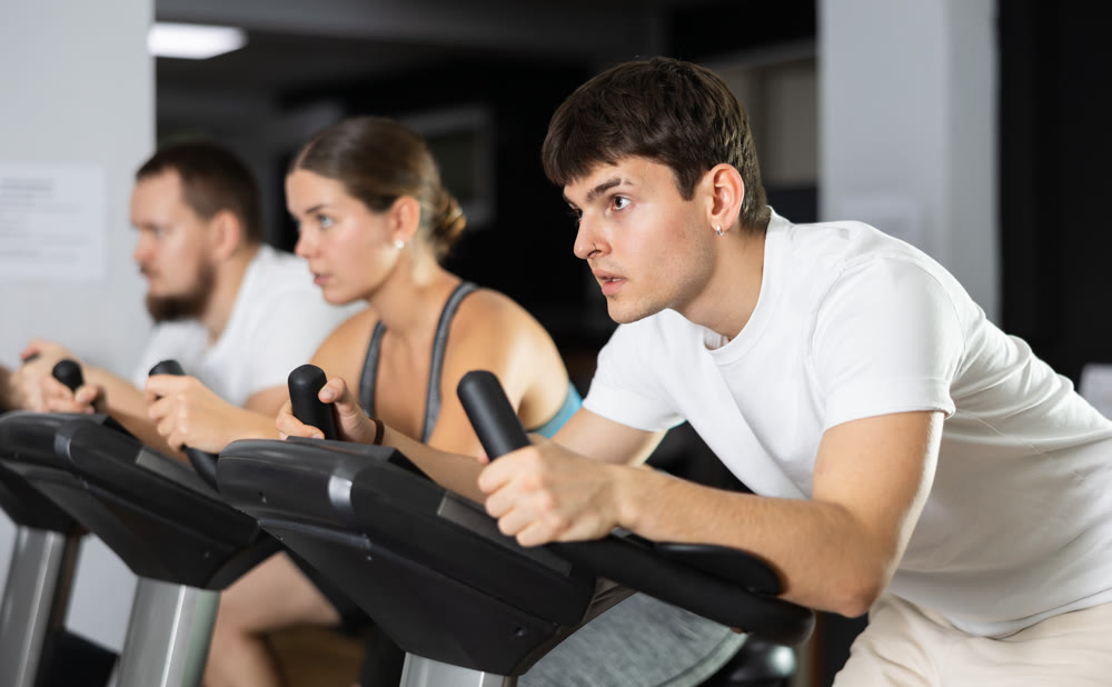 Focused guy works out with stationary bicycle during class at fitness club