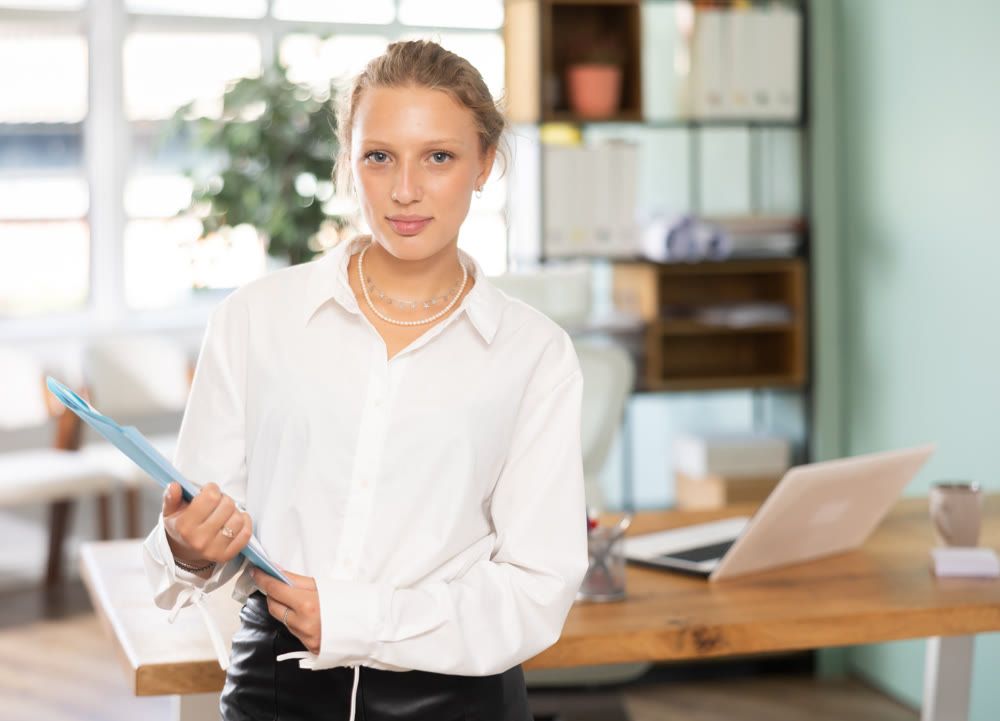 Young woman standing with document folder in office