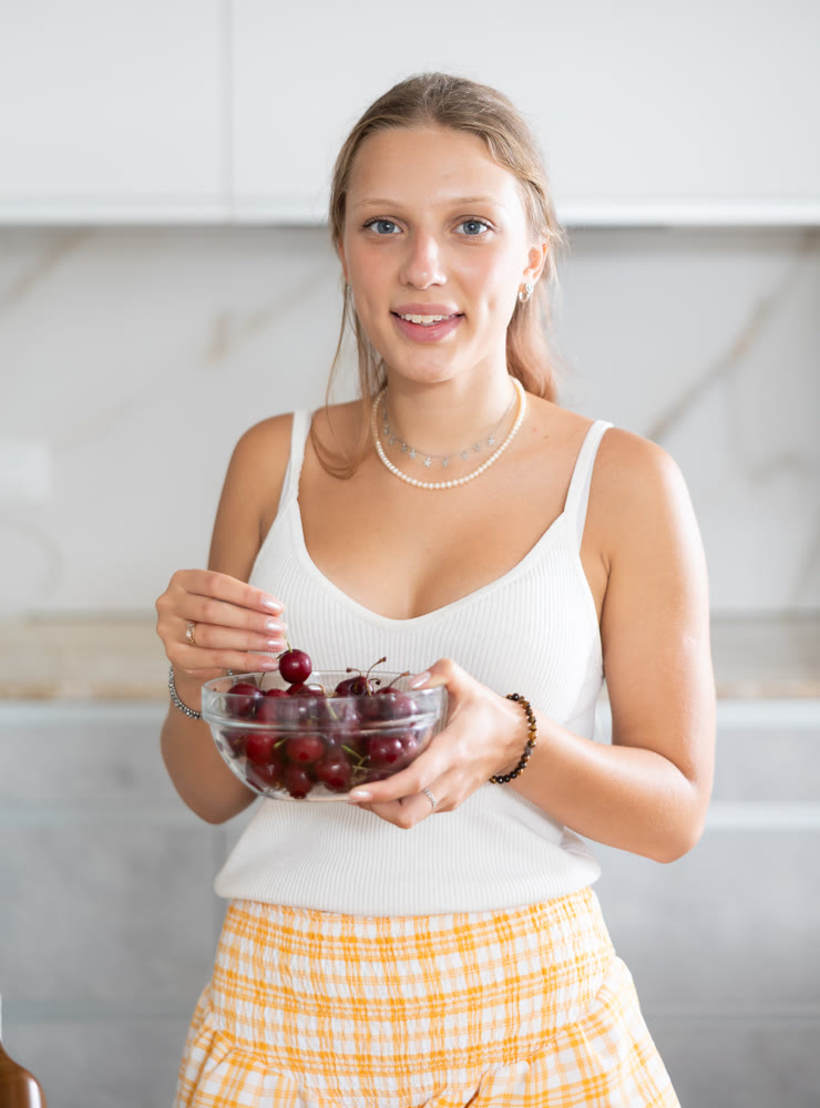 Young woman eating cherries in kitchen