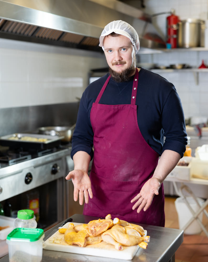 Store worker preparing raw chicken for cooking in ready-to-eat food section