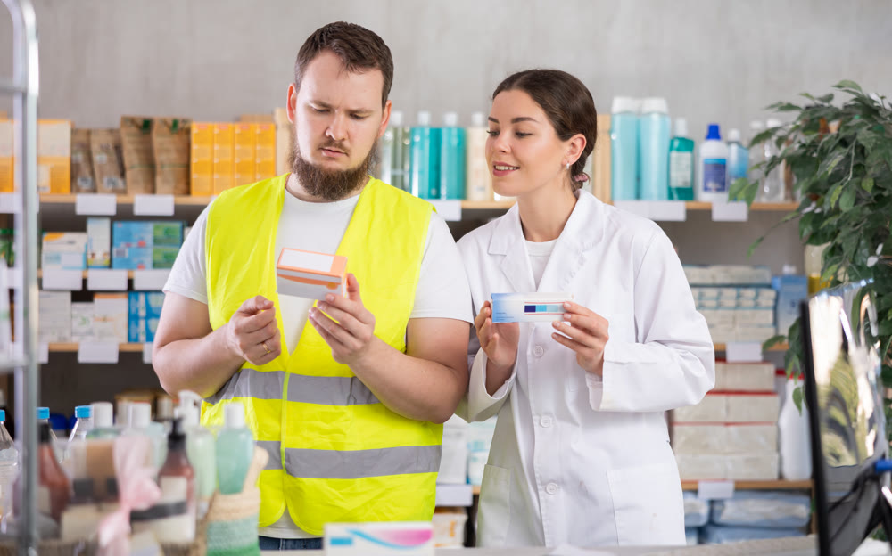 Laboring man builder buys pills at pharmacy, consulting with girl pharmacist