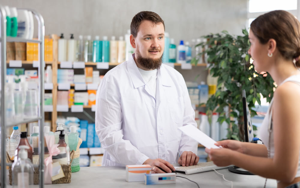 Man pharmacist looking for prescription on computer for buyer