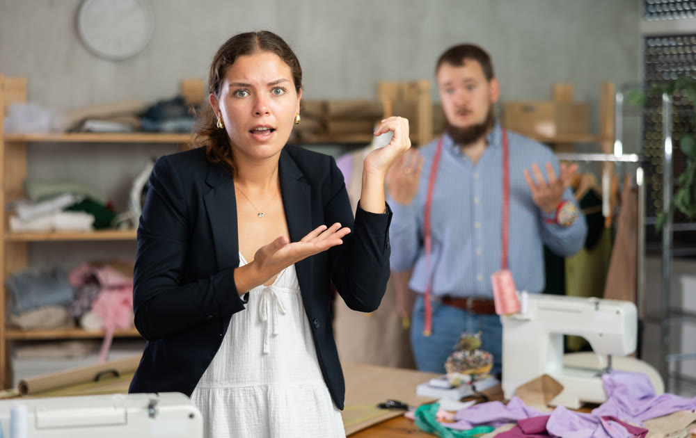 Dissatisfied young girl looking at ready jacket in fashion studio