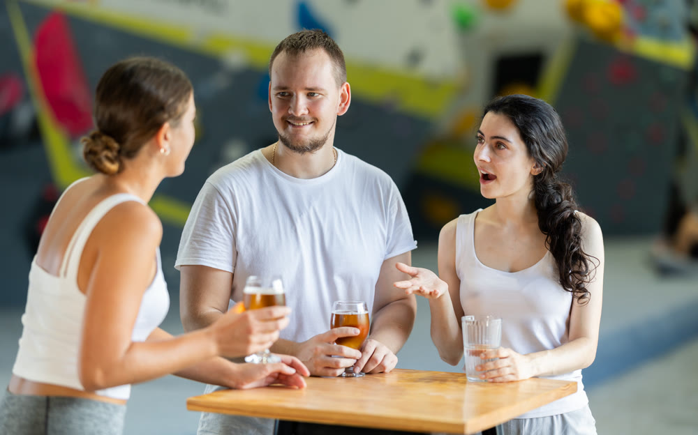 Man and two women talk at table on climbing wall