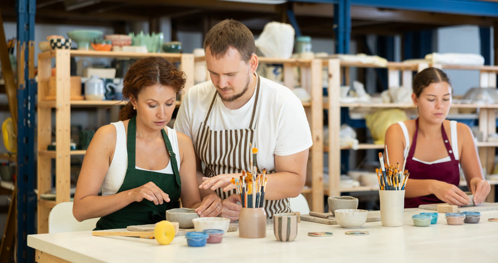 Potter explains to students how to shape clay to make beautiful ceramic dishes