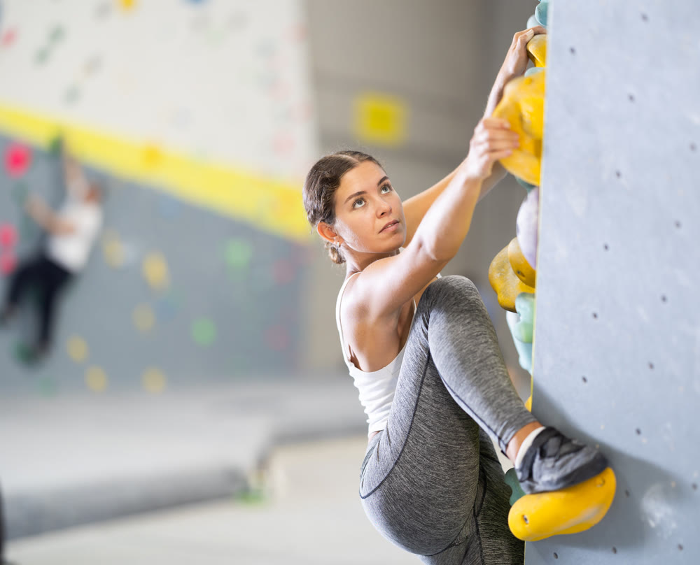 Young woman practicing rock climbing on climbing wall