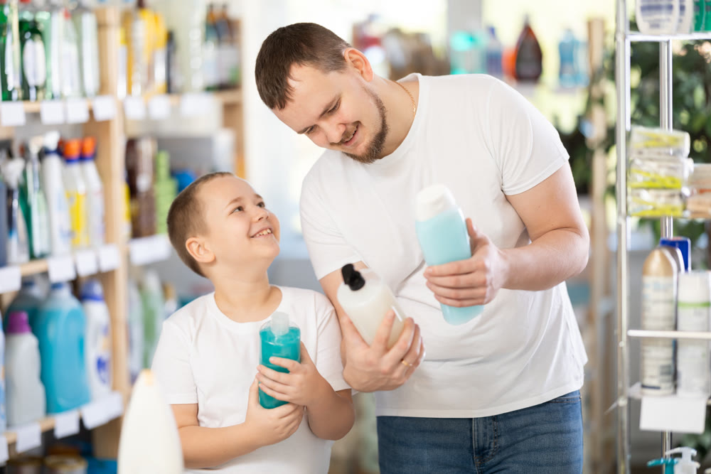 Schoolboy son and dad are choosing shower gel in store