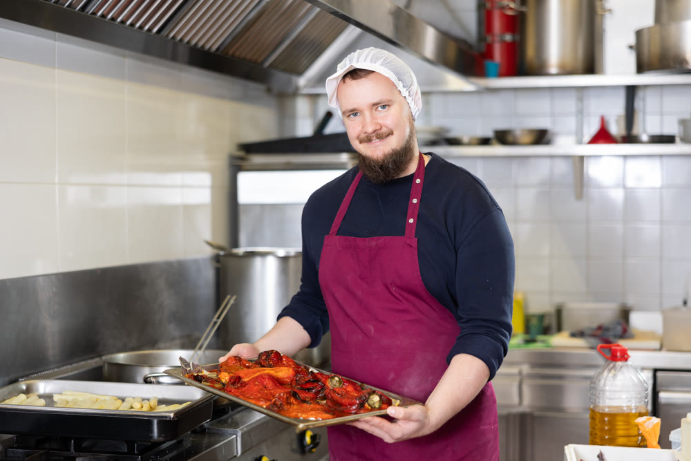 Man prepares delicious food on stove stewed red bell peppers