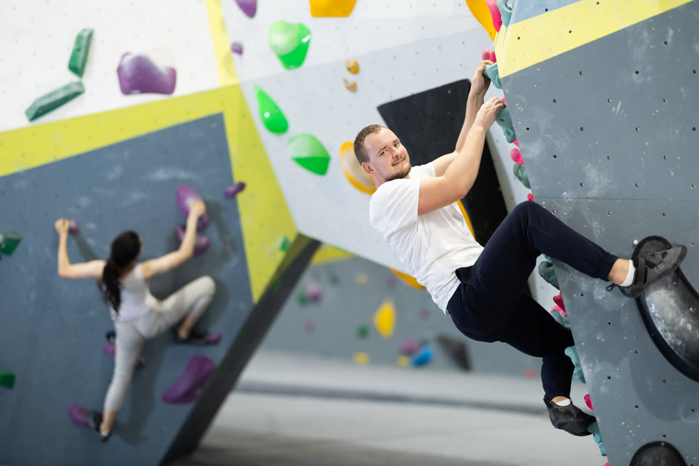 Man climbing a tall, indoor, man made rock climbing wall