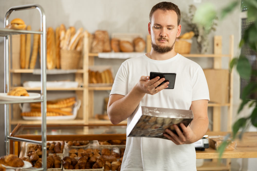 Man customer at bakery scans QR code on cookie package using phone camera
