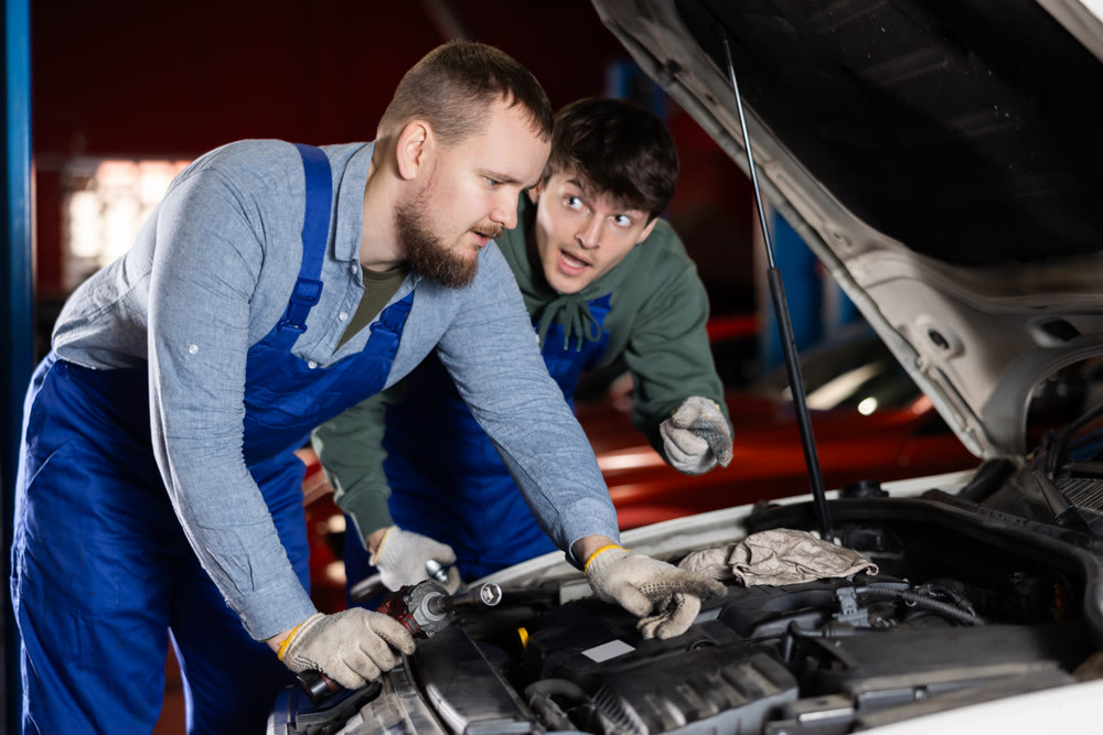 Two mechanics consult about repairing a car