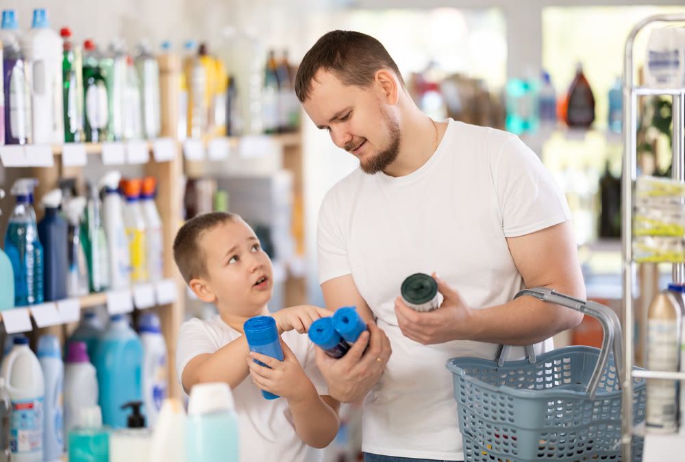 Schoolboy son and dad are choosing trash bags in store