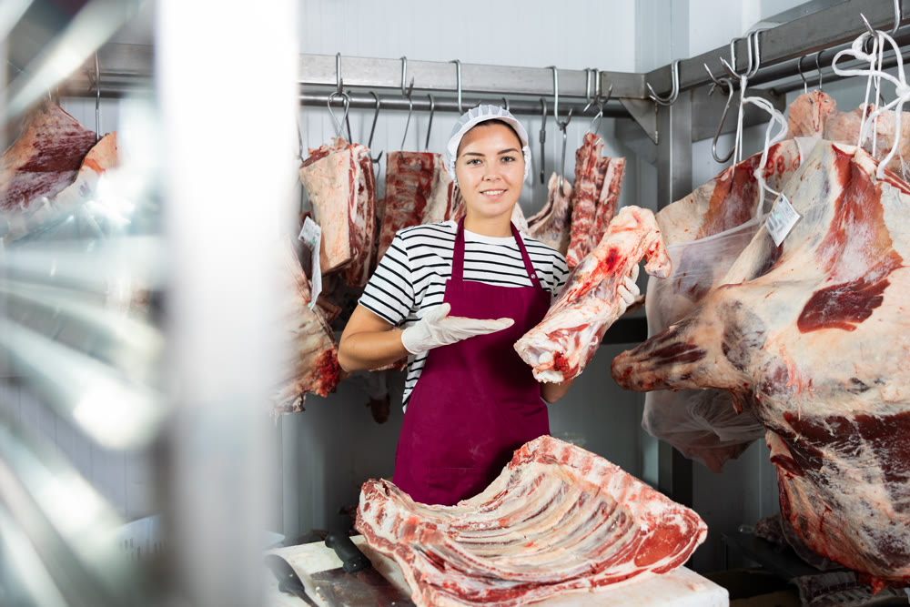 Butcher shop saleswoman preparing beef cuts for sale