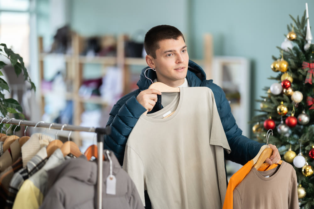 Young man chooses t-shirt in clothing store