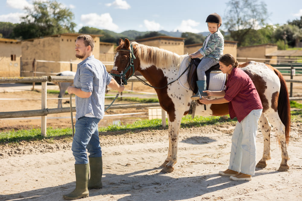 Young man leading horse with boy on horseback