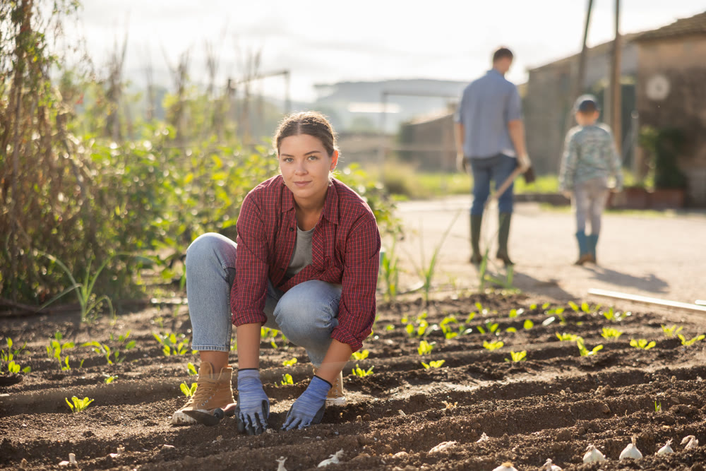 Young woman planting seeds in field