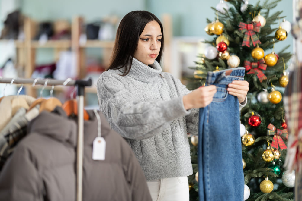 Girl shopper chooses jeans in clothing store before Christmas
