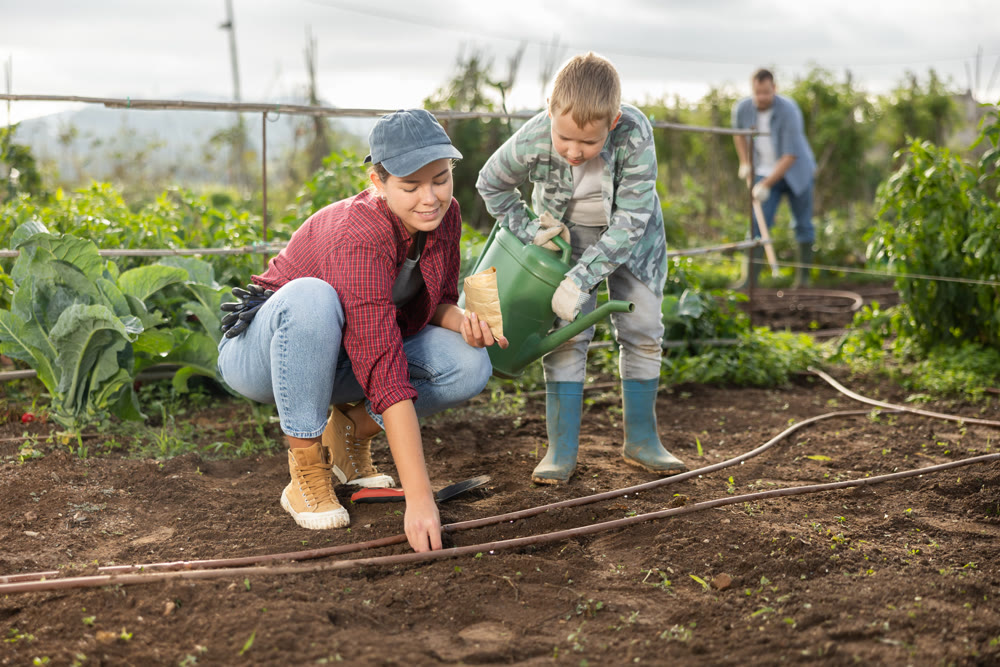 Woman planting seeds boy watering beds