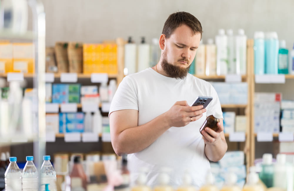Male buyer scans code on cough syrup to check expiration date