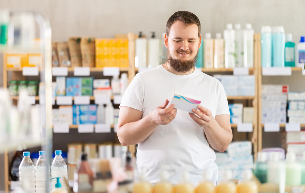 Young man chooses pills at pharmacy