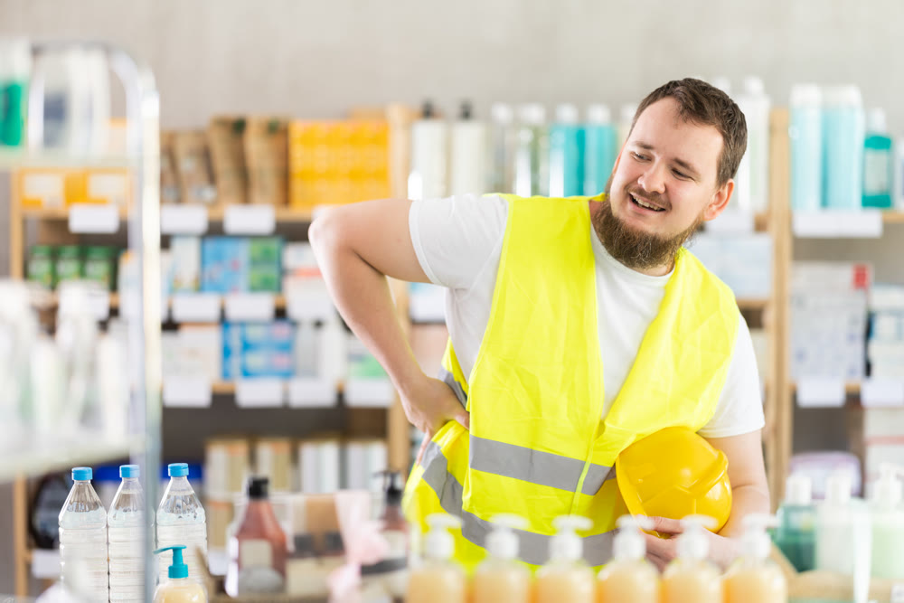 Young man builder with back pain at pharmacy