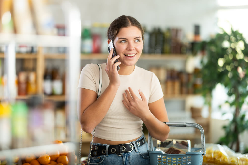 Young woman choosing groceries while talking on phone