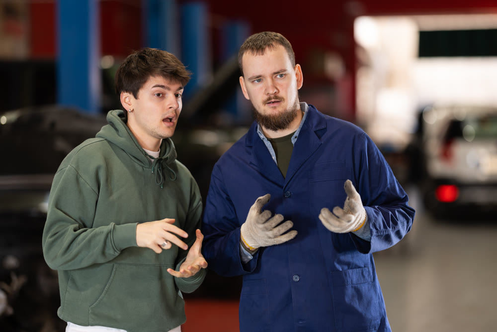Guy discusses further repairs to his car with car mechanic at car service center