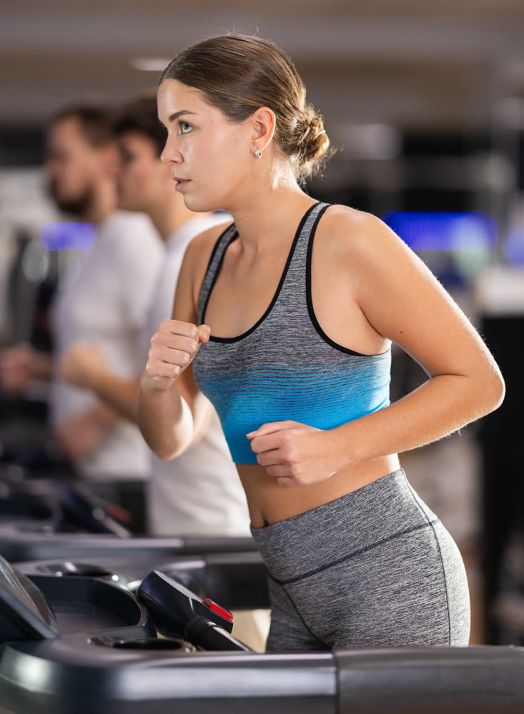 Focused girl works out with treadmill during class at fitness club