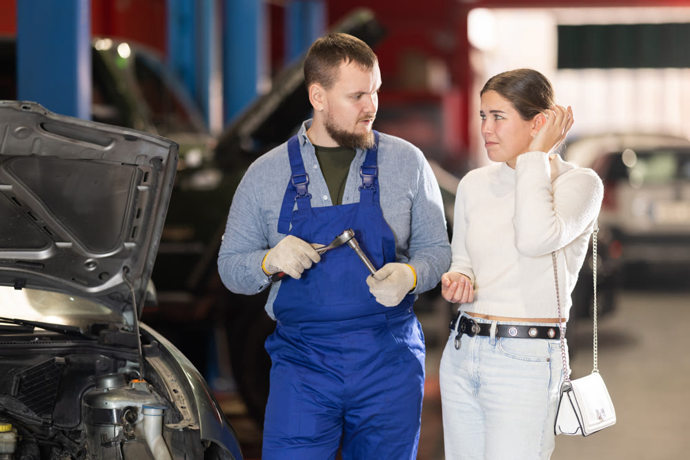 female customer of a car service consults with a mechanic