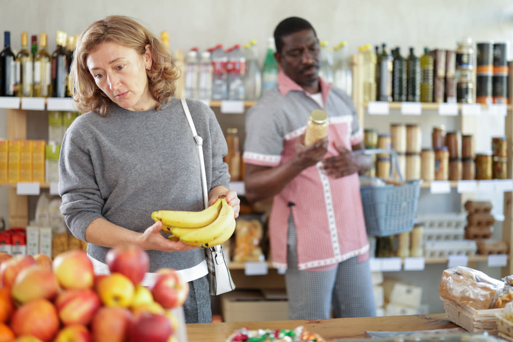 Female shopper carefully selects the freshest bananas in supermarket