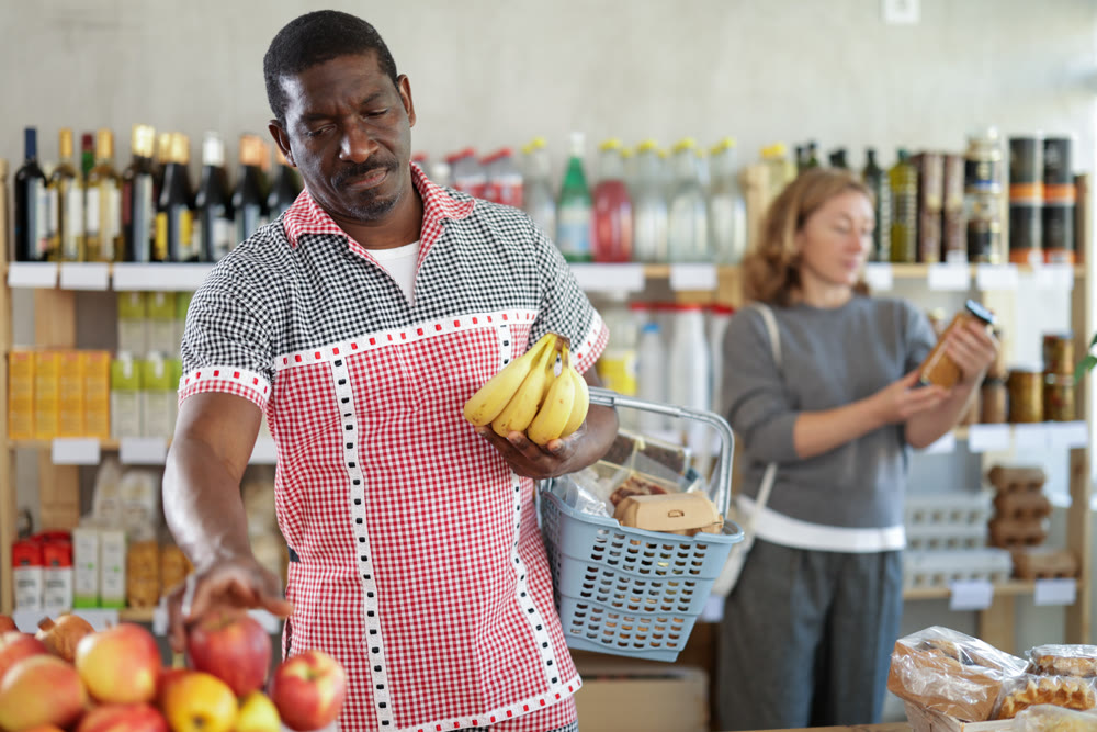 Male shopper carefully selects the freshest bananas in supermarket