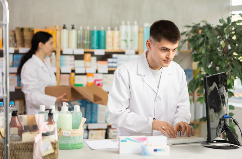 Portrait of male pharmacist working at computer in pharmacy