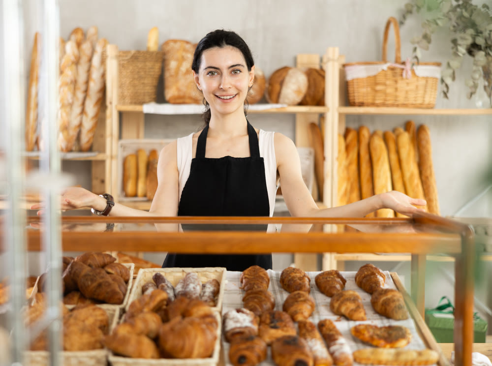 Young woman seller at showcase with pastries