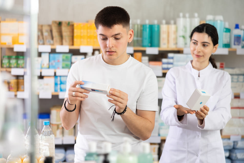 Man choosing ointment with help from pharmacist