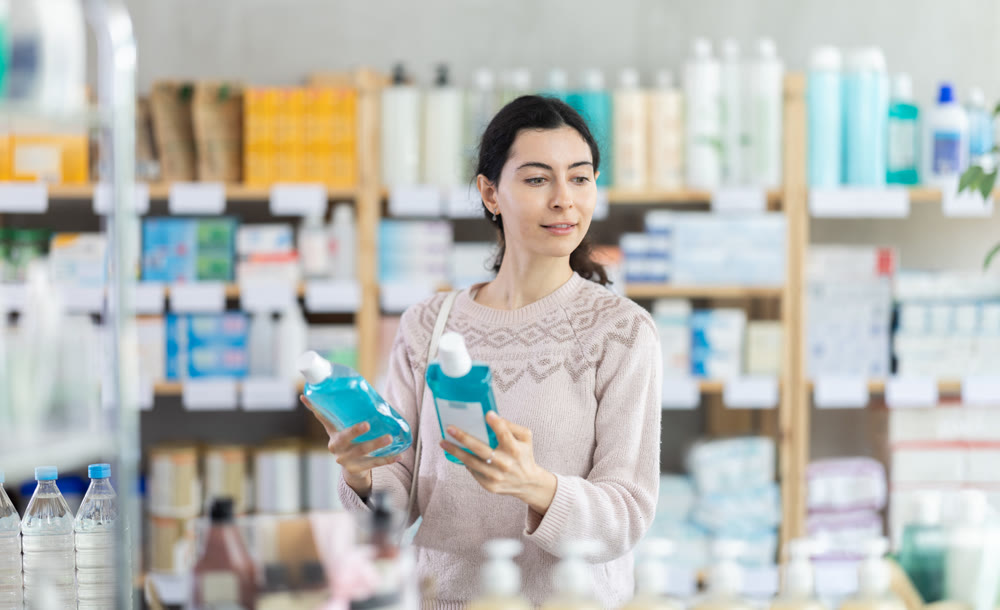 Young woman chooses mouthwash at pharmacy