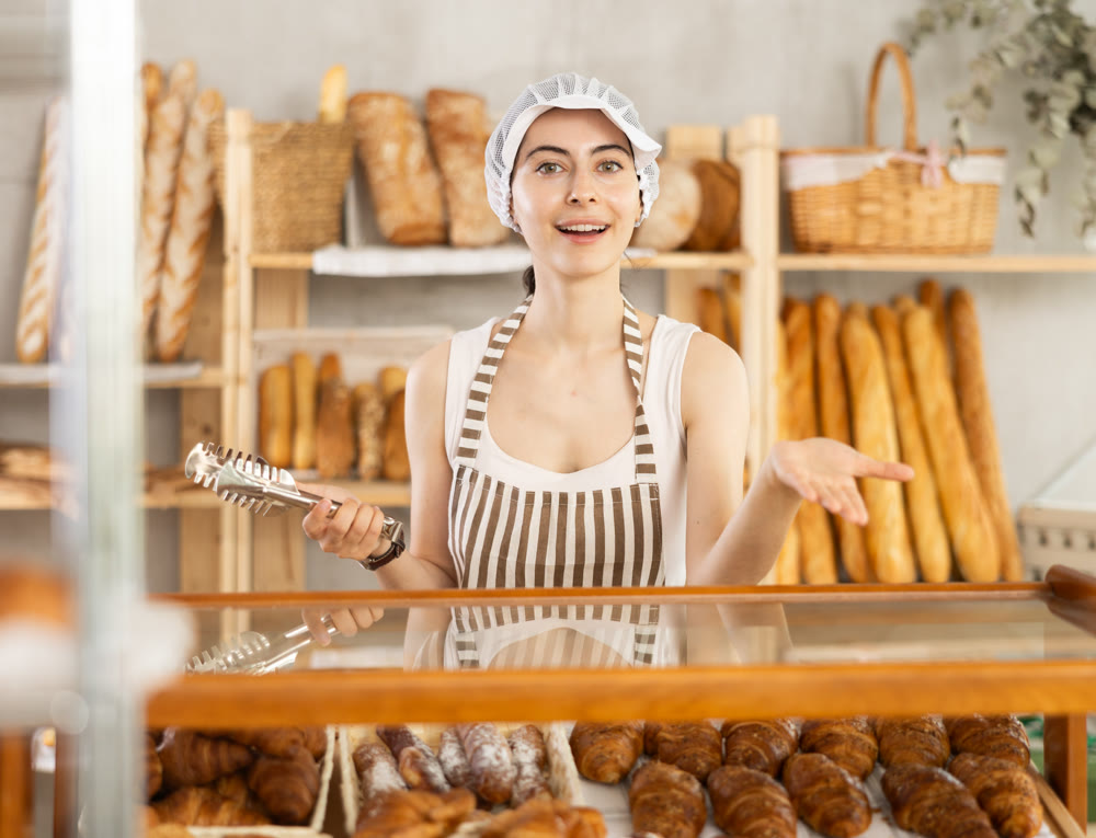 Young woman seller at showcase with pastries