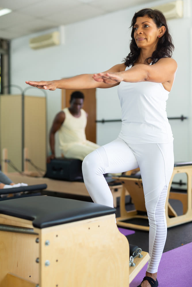 Latin woman perform exercises on combined chair